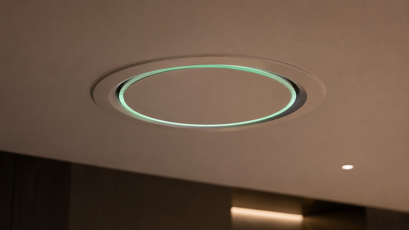 Close-up of Survair flush circular ceiling diffuser with recessed mint LED status ring and clean plaster integration.